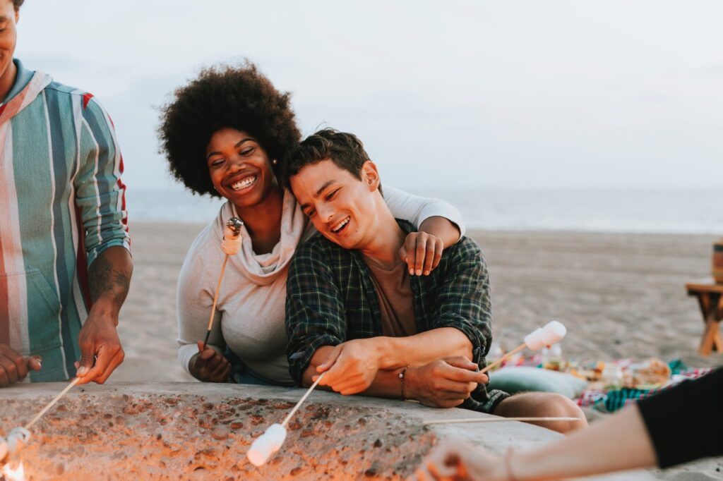 man and woman toasting marshmallows in fire pit