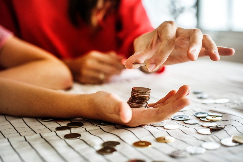 woman stacking coins on hand of child