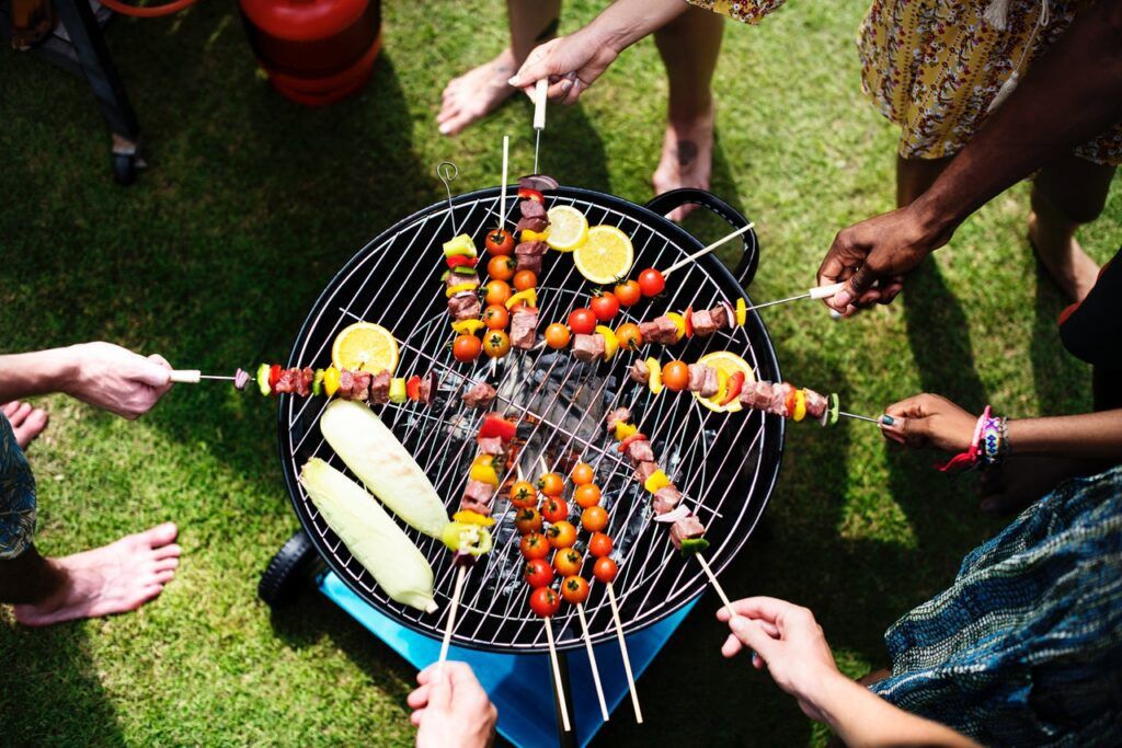 group of people barbecuing kebabs