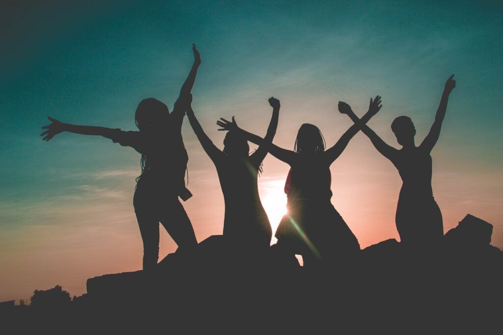 silhouette of four women raising their hands