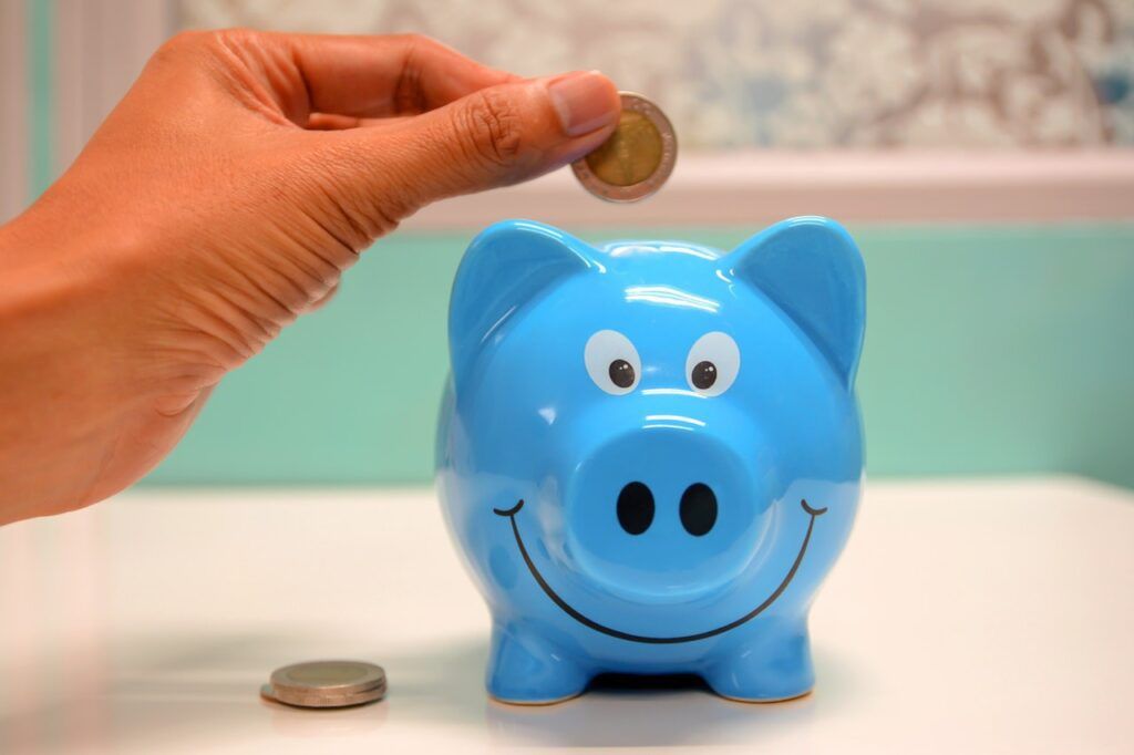 person putting coin inside blue piggybank