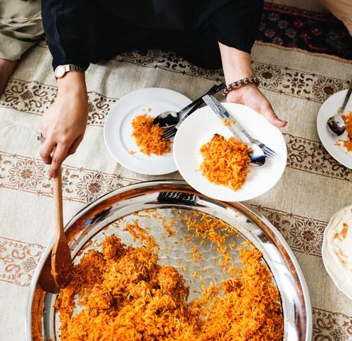 person putting cooked rice on plate