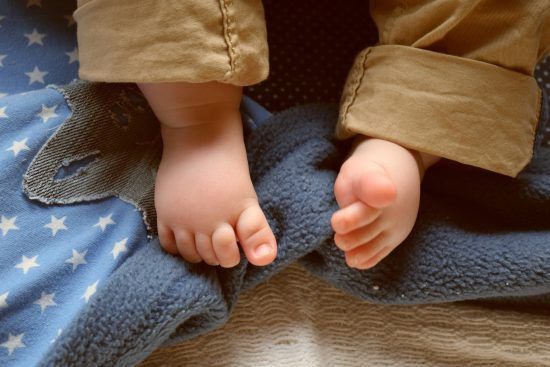 The feet of a baby that is laying on a baby blanket.