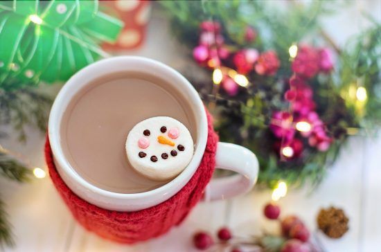 Holiday hot chocolate in a mug that has a drink cozy on it.