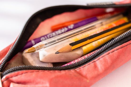 Pens and pencils inside of a zipper pouch.